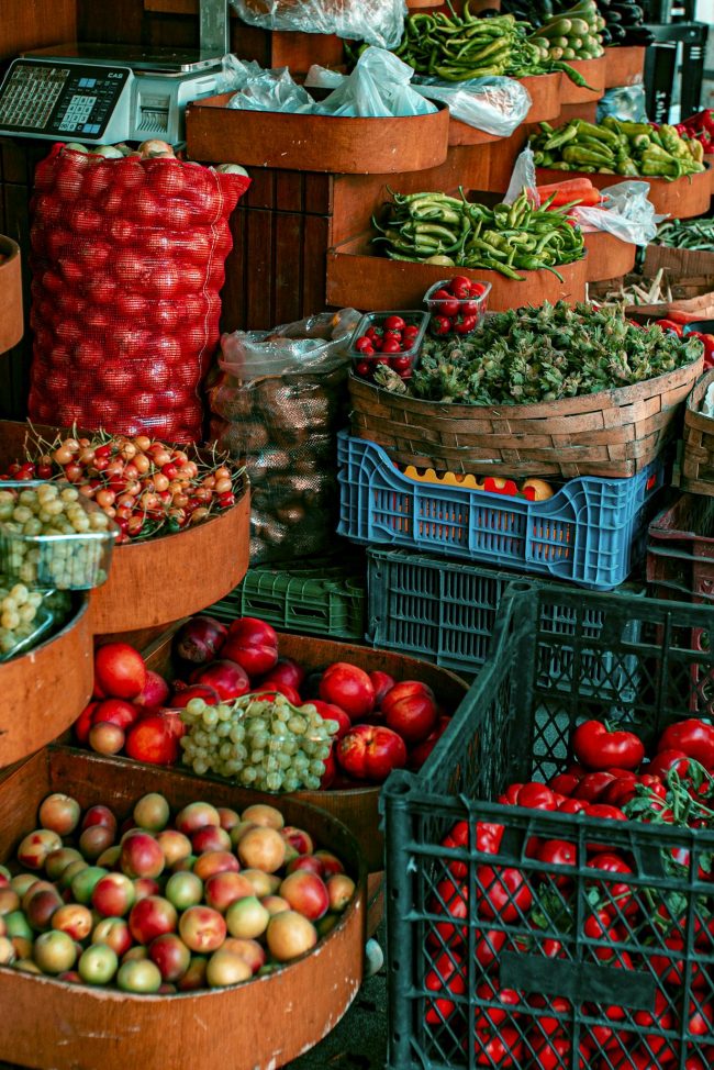 A colorful display of fresh fruits and vegetables at a bustling open-air market.